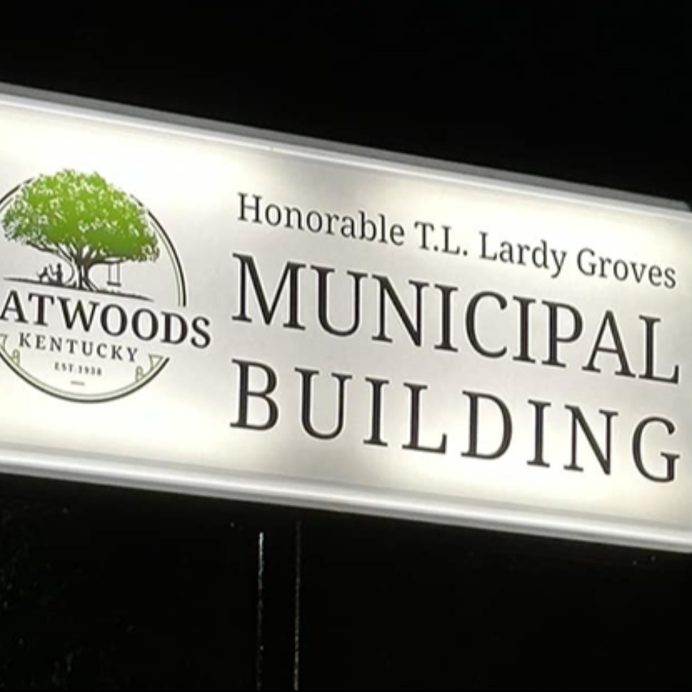 Illuminated sign for the Flatwoods, Kentucky Municipal Building, titled “Honorable T.L. Lardy Groves Municipal Building,” featuring the Flatwoods logo with a large green tree.
