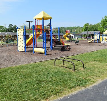 Colorful playground with slides, climbing structures, and mulch ground covering, located in B.F. Crager Community Park.