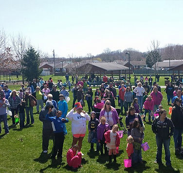 Large crowd of families and children gathered on the grass for a springtime event at B.F. Crager Community Park.